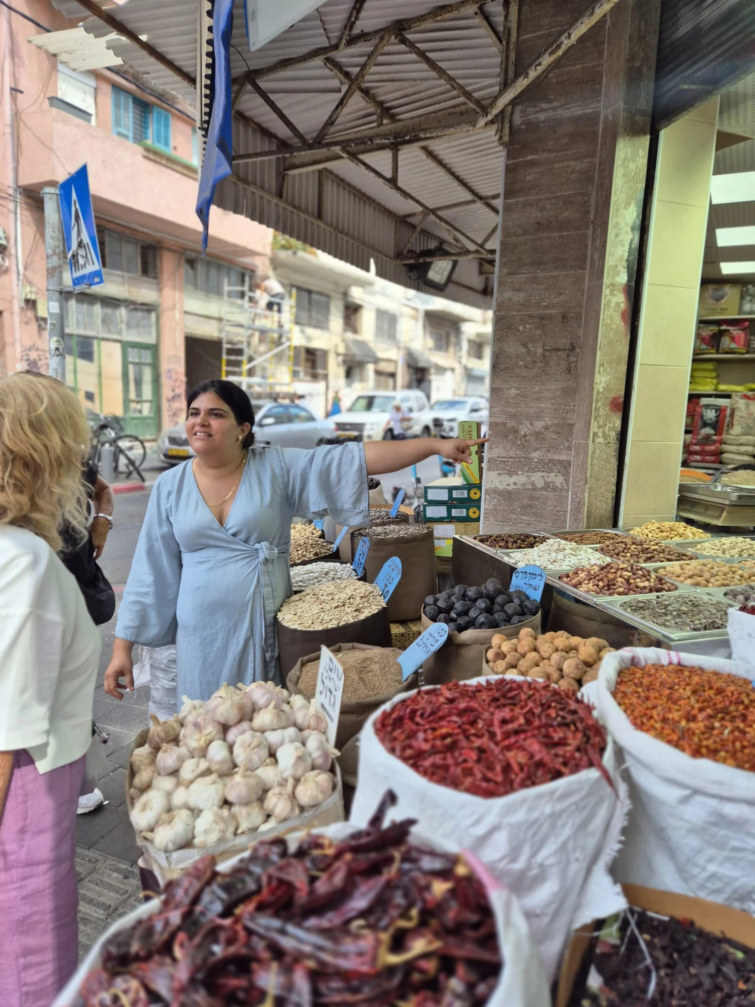 ענבל מדריכה ליד דוכן צמחים ותבלינים בשוק לוינסקי